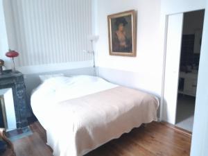 a bedroom with a white bed with a picture on the wall at Beausejour in Lézignan-Corbières