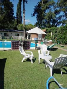 three white chairs and an umbrella next to a pool at Quinta San Antonio in Luján +32 photos