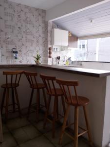 een keuken met een aanrecht met vier barkrukken bij Apartamento Arara Azul in Cabo Frio