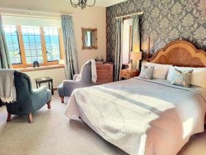 Un dormitorio con una cama grande y una silla. en Luxury Bed And Breakfast at Bossington Hall in Exmoor, Somerset, en Porlock