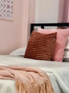 a bed with pink and brown pillows on it at Rosa by Kutys Inn in Canaman +2 photos