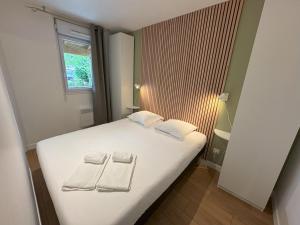 a bedroom with a white bed with towels on it at Les Cottages Du Lac in Parentis-en-Born +68 photos