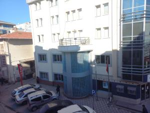a white building with cars parked in a parking lot at körfez otel in Edremit