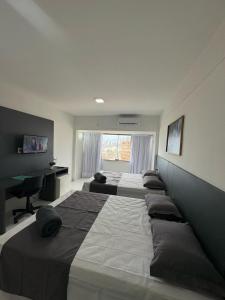 a row of beds in a bedroom with a desk at MoviHosts Ayambra I Próximo ao Centro in Natal