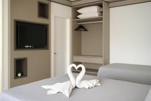 2 cygnes blancs assis au-dessus d'un lit dans l'établissement Suíte Privilegiada no Centro - Golden Dolphin, à Caldas Novas