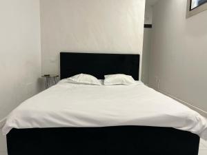 a white bed with a black headboard in a room at Garsoniera Zona Stadion in Craiova