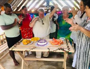 eine Gruppe von Menschen, die um einen Tisch mit Kuchen stehen in der Unterkunft Scenic Cottage Sigiriya in Sigiriya