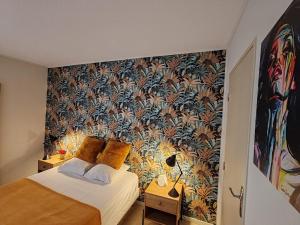 Un dormitorio con una cama con papel pintado floral. en La Pause Confortable, en Perpiñán