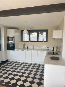 a kitchen with white cabinets and a checkered floor at maison vue mer avec terrasse in Brest +7 photos