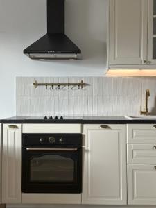 una cucina con forno nero e armadietti bianchi di Przedmiejska2 Apartment a Breslavia