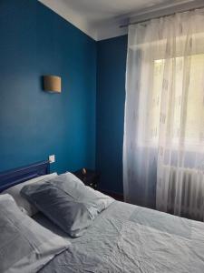 a bedroom with a bed with a blue wall and a window at MAISON APPARTEMENT LA BAULE LES PINS in La Baule