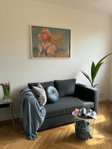 a living room with a blue couch and a painting at Apartament Lady Eleven in Gdańsk