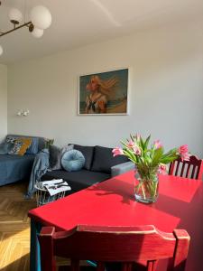 a living room with a red table with flowers on it at Apartament Lady Eleven in Gdańsk