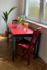 a red dining room table with two chairs and a window at Apartament Lady Eleven in Gdańsk