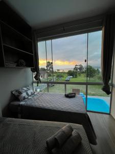 - une chambre dotée d'une grande fenêtre offrant une vue sur la piscine dans l'établissement Apartamento de frente para lagoa -Ap 101, à Laguna