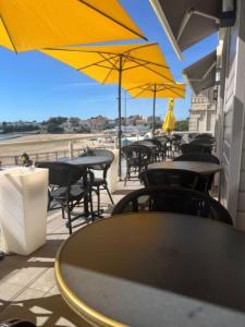 una fila de mesas y sillas con sombrillas amarillas en Hôtel The Originals Miramar, Royan Pontaillac, en Royan