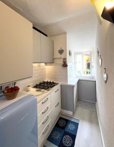 une cuisine avec des armoires blanches et un four à plaques de cuisson dans l'établissement Alloggetto a Chiavari, à Chiavari