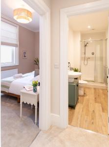 a bedroom with a bed and a bathroom with a sink at Stunning Townhouse by the sea, Hot Tub sleeps 17 in Seaton