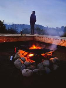 uma pessoa em pé ao lado de uma fogueira em Tinyhouse Pichi - vida lenta en Patagonia Costa em Calbuco