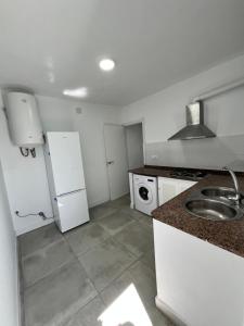 eine weiße Küche mit Spüle und Kühlschrank in der Unterkunft Casa Ianira in El Puerto de Santa María