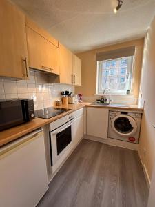 une petite cuisine avec un évier et un micro-ondes dans l'établissement One room with parking space, à Édimbourg