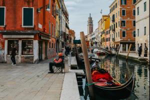 a person sitting in a chair next to a canal with a gondola at Serenity in Mestre