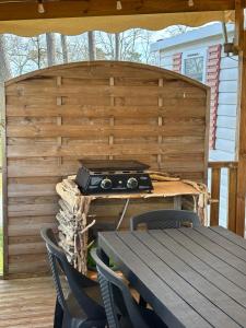 an outdoor grill with a table and chairs on a deck at Lodge du Sangla Mobil Home premium Village Vacances 4 étoiles Lège Cap Ferret in Lège-Cap-Ferret
