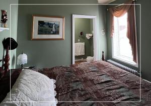 布克塔谢Le Gîte De La Sagouine的一间卧室设有一张床、一个窗口和一面镜子