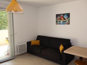 Una sala de estar con un sofá negro y una mesa. en Le Soleil de Mougins, en Mougins