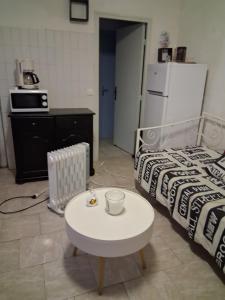 a room with a coffee table and a bed and a refrigerator at Studio plage in Santa-Maria-di-Lota