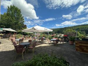 eine Terrasse mit Tischen und Stühlen und einem Sonnenschirm in der Unterkunft Landgasthaus Klosterhof in Fischbach