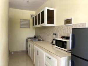 a kitchen with white cabinets and a black refrigerator at Apartamento Costero 2 en Las Galeras in Las Galeras