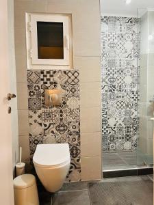 a bathroom with a toilet and a tv on the wall at Apollo Peraia Apartment in Perea +24 photos