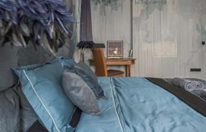 Schlafzimmer mit einem Bett mit blauen Kissen und einem Schreibtisch in der Unterkunft Old Town Hideaway in Vilnius