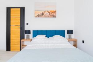 a white bed with a blue headboard and two tables at Złota Willa - 100m od plaży in Jastarnia