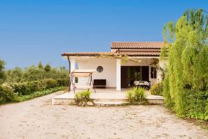 a small white house with a dirt road at Trullo Della Murgia - Villa in Castel del Monte