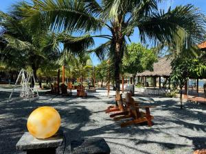a park with benches and palm trees and a playground at River Homestay in Hàm Tân