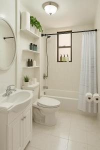 a white bathroom with a toilet and a sink at Lemon Vibes room in New York