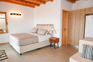 a white bedroom with a bed and a wooden ceiling at Porto Vista Milos in Adamas