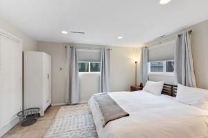 a bedroom with a large white bed and windows at Well appointed Lakefront home in White Lake