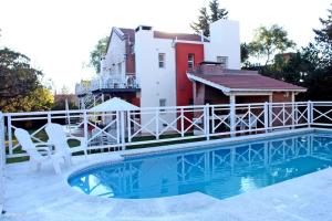 a house with a swimming pool and a white fence at Posada de las Sierras in Merlo