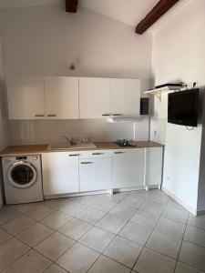 une cuisine avec des armoires blanches et une machine à laver dans l'établissement Studio tout confort, à La Crau