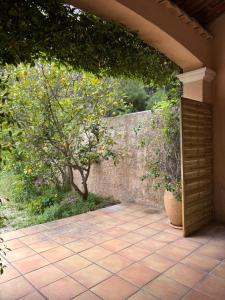 un patio extérieur avec un mur en pierre et un arbre dans l'établissement Studio tout confort, à La Crau
