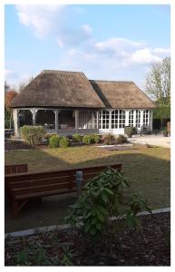 een gebouw met een rieten dak en een bank voor de deur bij Kamer 22 Bed & Breakfast in Poppel