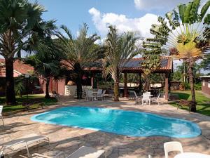a swimming pool with chairs and a gazebo at Chácara do Haras in Nova Odessa