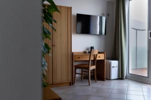 a room with a desk with a chair and a television at Hotel La Gioiosa in Finale Ligure