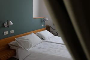 a bedroom with a bed with white sheets and pillows at Hotel La Gioiosa in Finale Ligure