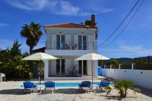 een huis met stoelen en parasols en een zwembad bij Villa Arcadia in Zakynthos