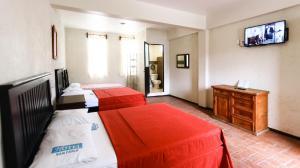 two beds in a room with a television on the wall at Hotel Guivá San Pablo in Hacienda Blanca