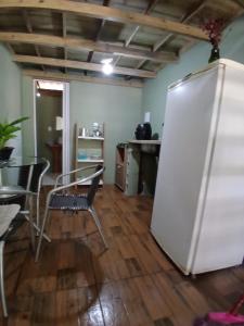 a room with a white refrigerator and a table and chairs at Tatiane cristino in Imbituba +5 photos